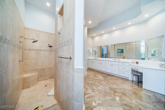 bathroom with tile walls, vanity, a tile shower, and a towering ceiling