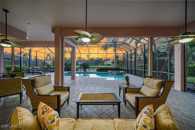 patio terrace at dusk featuring an outdoor living space, glass enclosure, and ceiling fan