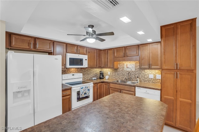 kitchen featuring white appliances, a tray ceiling, decorative backsplash, and sink