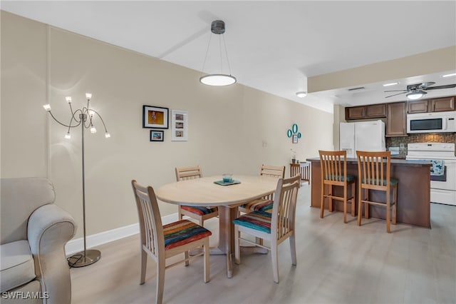 dining room featuring light hardwood / wood-style floors and ceiling fan with notable chandelier