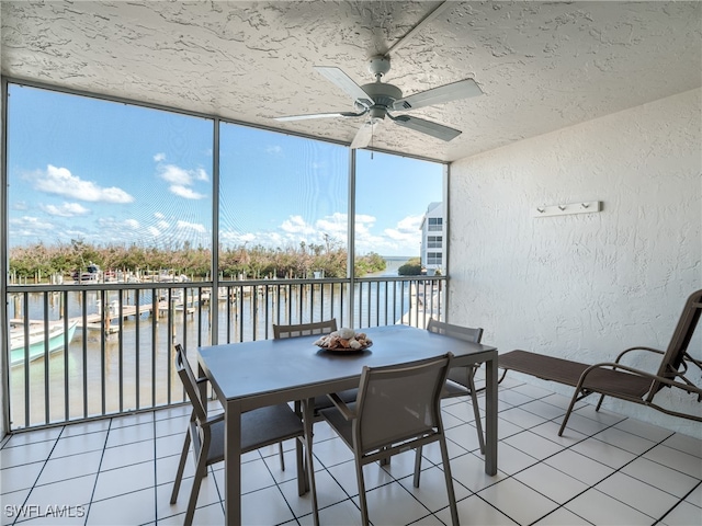 unfurnished sunroom with ceiling fan and a water view