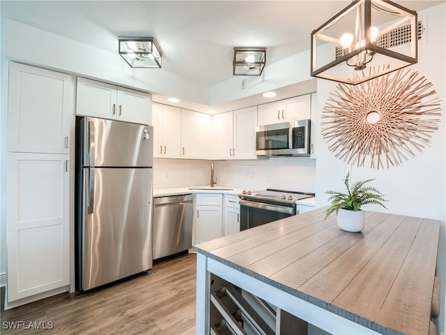 kitchen with white cabinets, light wood-type flooring, and appliances with stainless steel finishes