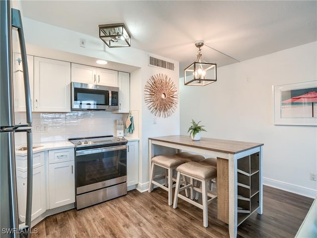 kitchen featuring wood finished floors, visible vents, light countertops, appliances with stainless steel finishes, and backsplash