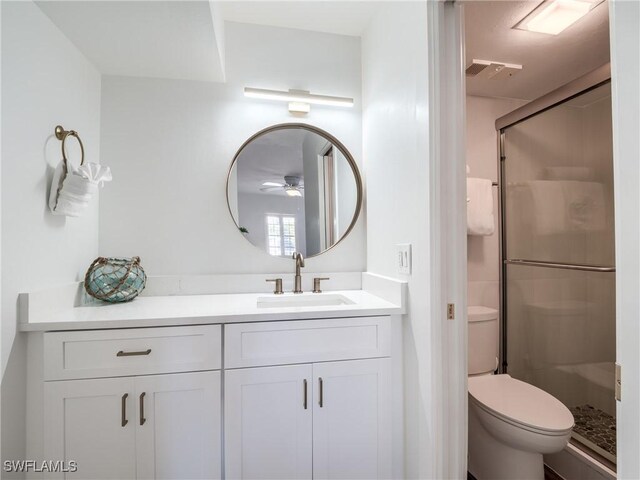 bathroom featuring vanity, ceiling fan, toilet, and a shower with door