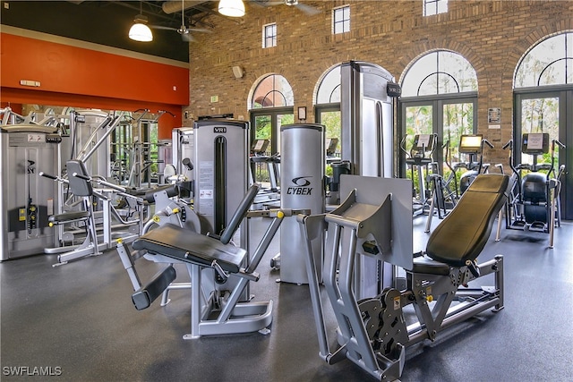 workout area featuring a wealth of natural light, brick wall, and a high ceiling