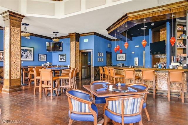 dining area featuring hardwood / wood-style flooring, ornamental molding, and decorative columns