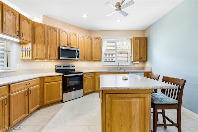 kitchen featuring a center island, sink, stainless steel appliances, a kitchen breakfast bar, and light tile patterned floors