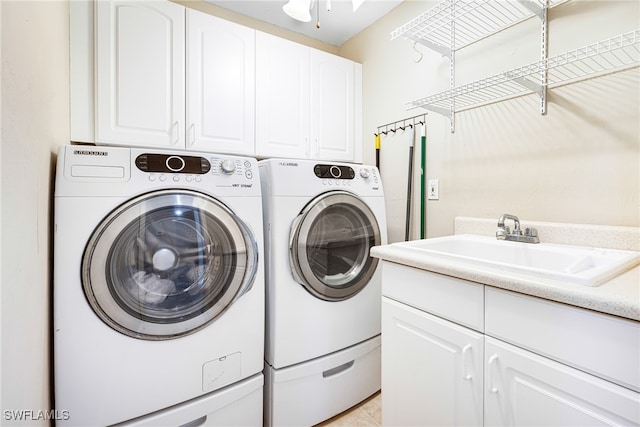 washroom with cabinets, independent washer and dryer, and sink