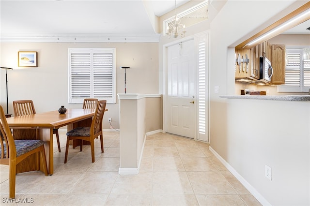 tiled dining room featuring a notable chandelier and ornamental molding