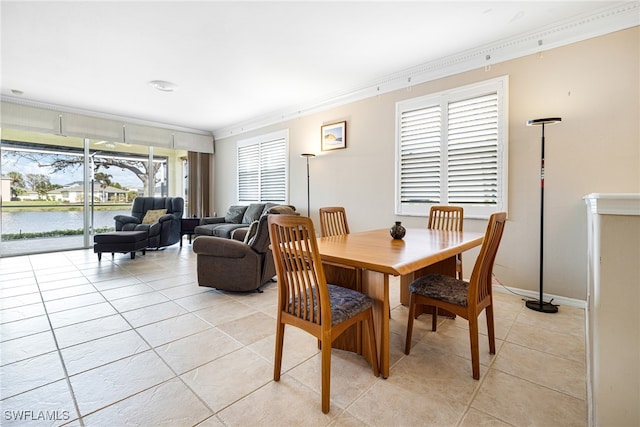 tiled dining space with a water view and ornamental molding