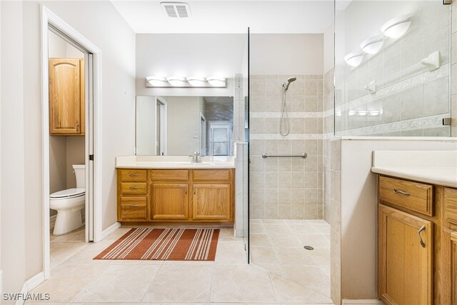 bathroom featuring tiled shower, tile patterned floors, vanity, and toilet