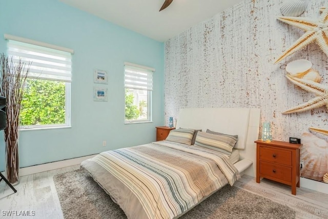 bedroom featuring multiple windows, ceiling fan, and hardwood / wood-style floors