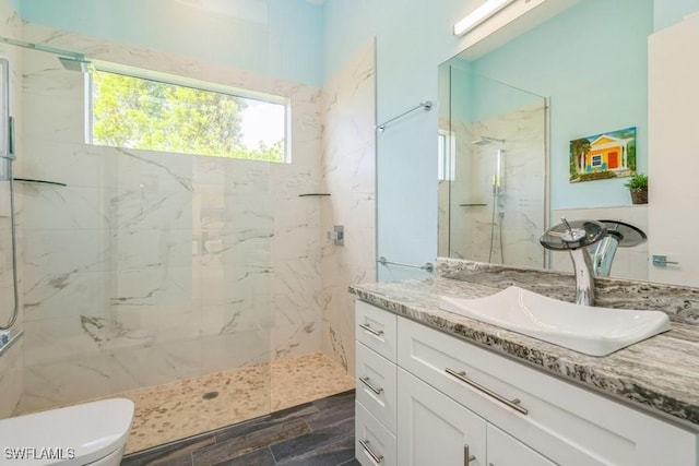 bathroom with tiled shower, vanity, and toilet