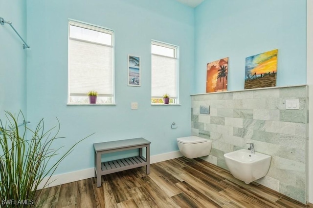 bathroom with hardwood / wood-style flooring, toilet, tile walls, and a bidet