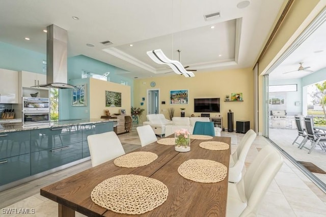 dining space featuring ceiling fan and a raised ceiling