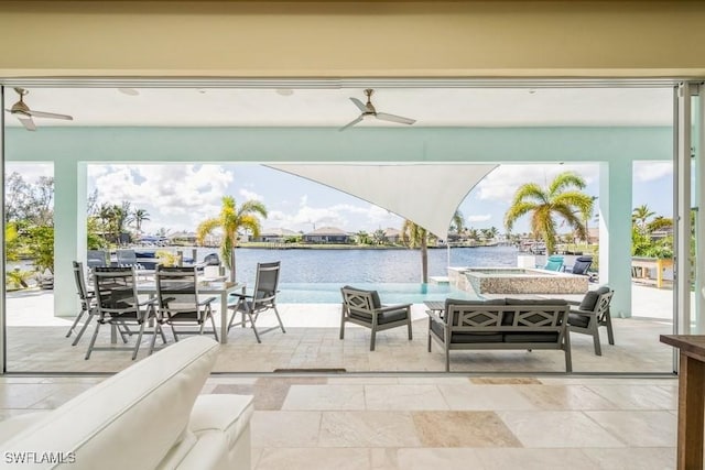 view of patio with ceiling fan, a water view, and an outdoor living space