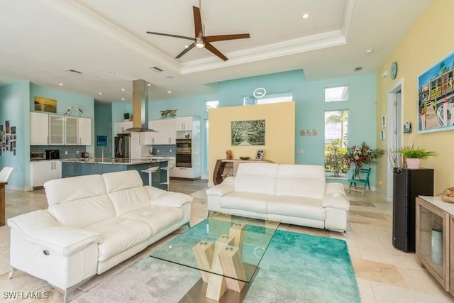 living room featuring ceiling fan, a raised ceiling, and sink