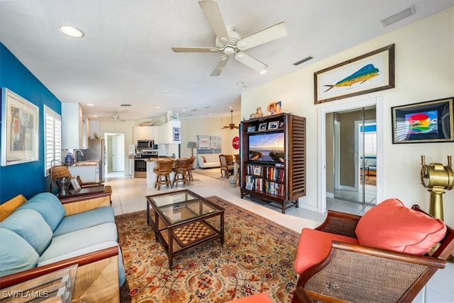 tiled living room featuring ceiling fan, a healthy amount of sunlight, and sink