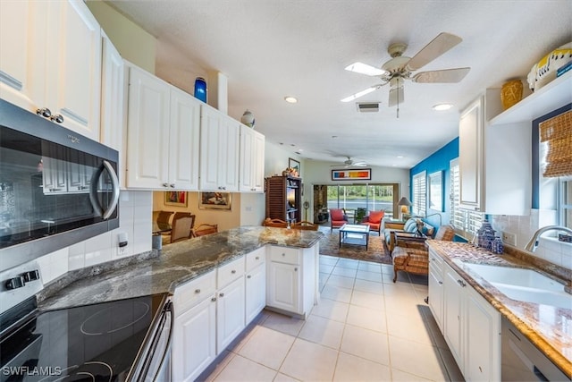 kitchen with kitchen peninsula, appliances with stainless steel finishes, sink, white cabinetry, and lofted ceiling