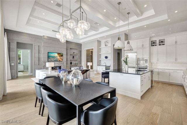 dining room featuring built in shelves, light hardwood / wood-style floors, a raised ceiling, and sink