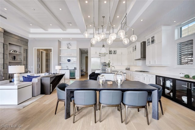 dining room with beamed ceiling, built in shelves, and light hardwood / wood-style floors