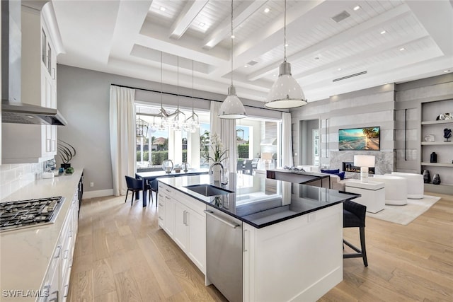 kitchen with stainless steel appliances, sink, decorative light fixtures, white cabinets, and light hardwood / wood-style floors