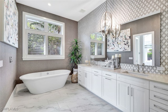 bathroom featuring vanity, a bath, and an inviting chandelier