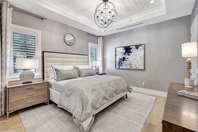 bedroom featuring hardwood / wood-style floors, multiple windows, and a tray ceiling