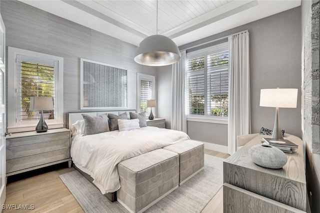 bedroom featuring a tray ceiling, light hardwood / wood-style flooring, multiple windows, and wood ceiling