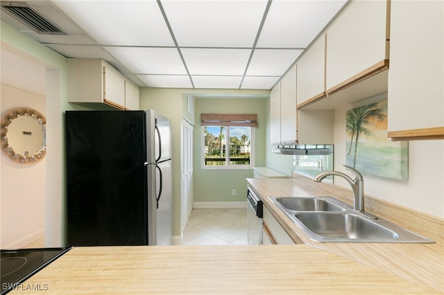 kitchen with light tile patterned flooring, a paneled ceiling, sink, refrigerator, and dishwasher