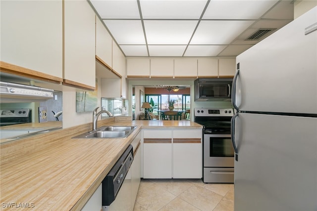 kitchen with a drop ceiling, appliances with stainless steel finishes, white cabinets, and sink