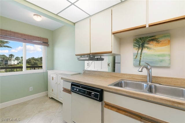 kitchen featuring white dishwasher, white cabinetry, sink, and light tile patterned floors