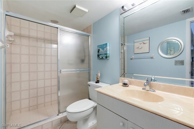 bathroom with a shower with door, vanity, toilet, and tile patterned floors