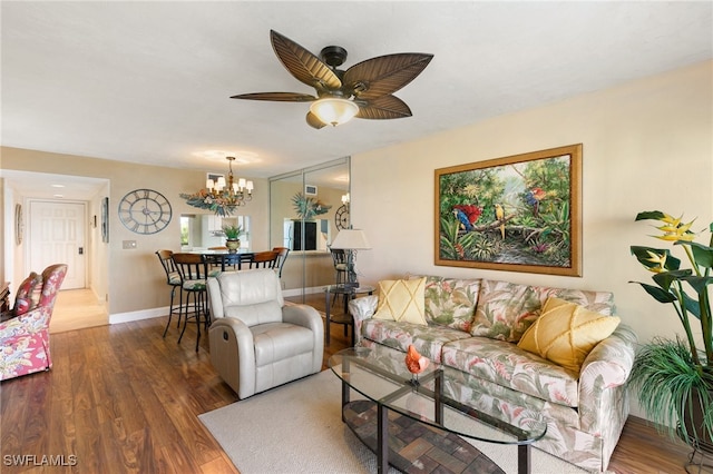 living room with ceiling fan with notable chandelier and dark wood-type flooring