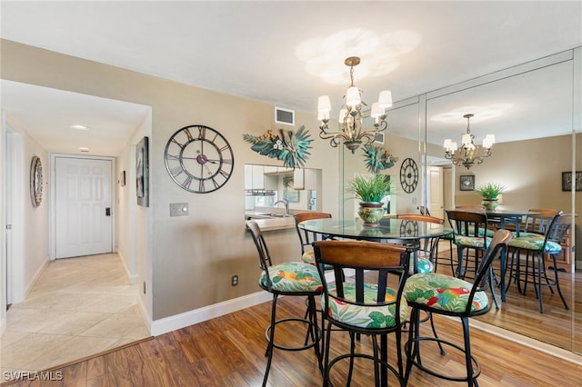 dining space with sink, light wood-type flooring, and a notable chandelier