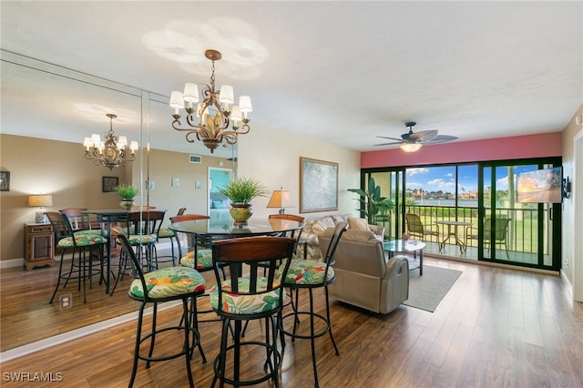 dining room featuring ceiling fan with notable chandelier and dark hardwood / wood-style flooring