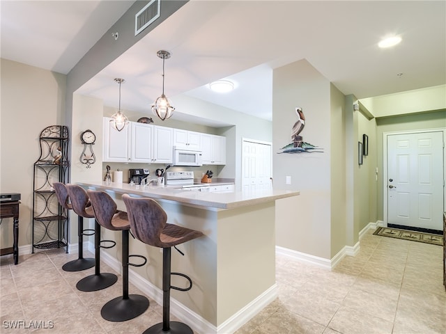 kitchen with kitchen peninsula, a kitchen breakfast bar, white appliances, white cabinets, and hanging light fixtures