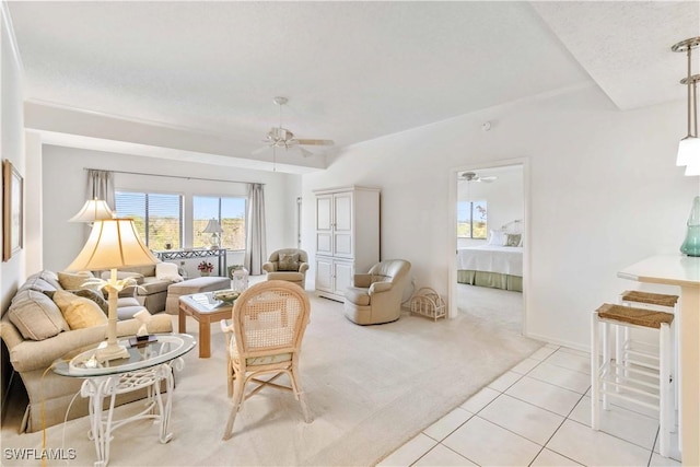 living room featuring ceiling fan, light colored carpet, and a textured ceiling