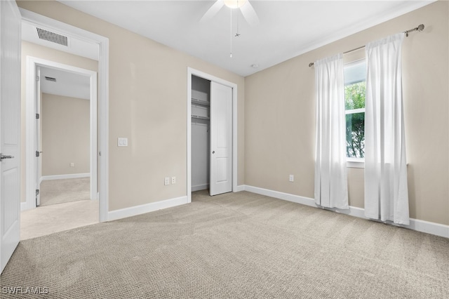 unfurnished bedroom with light colored carpet, ceiling fan, and a closet