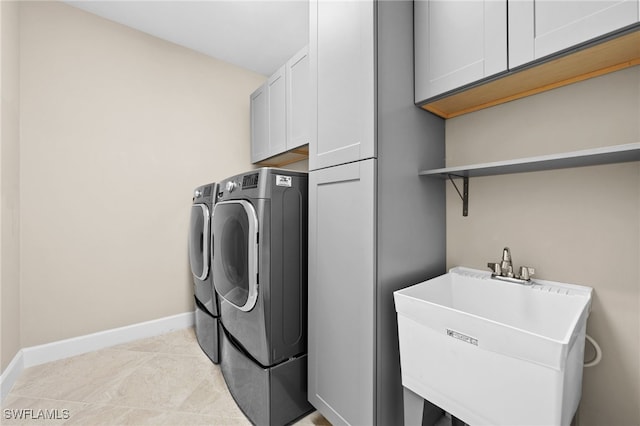 laundry area with cabinets, washer and clothes dryer, sink, and light tile patterned floors