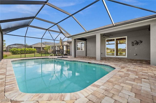 view of pool with glass enclosure, a patio, and ceiling fan