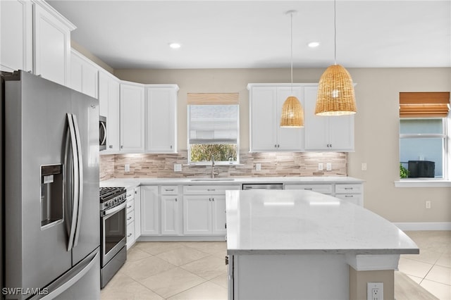 kitchen with stainless steel appliances, sink, hanging light fixtures, white cabinets, and decorative backsplash