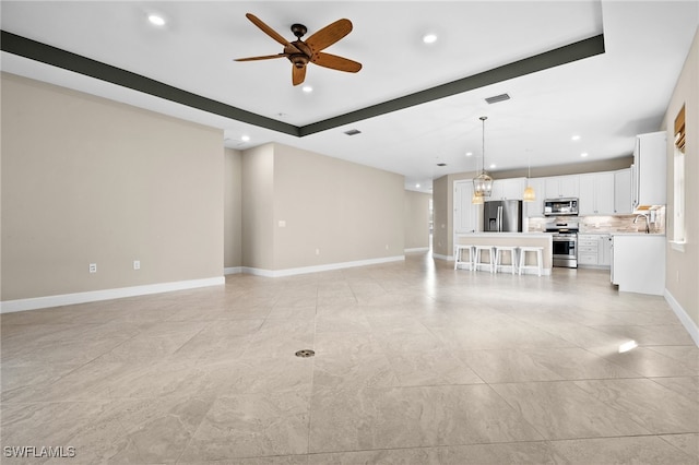 unfurnished living room featuring sink and ceiling fan