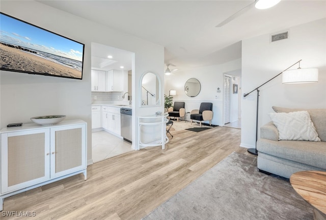 living room featuring light hardwood / wood-style floors, sink, and ceiling fan