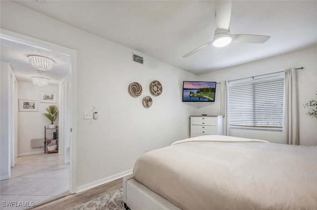 bedroom with ceiling fan with notable chandelier and light hardwood / wood-style flooring