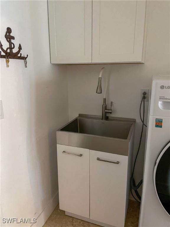 clothes washing area featuring cabinets, washer / clothes dryer, and sink