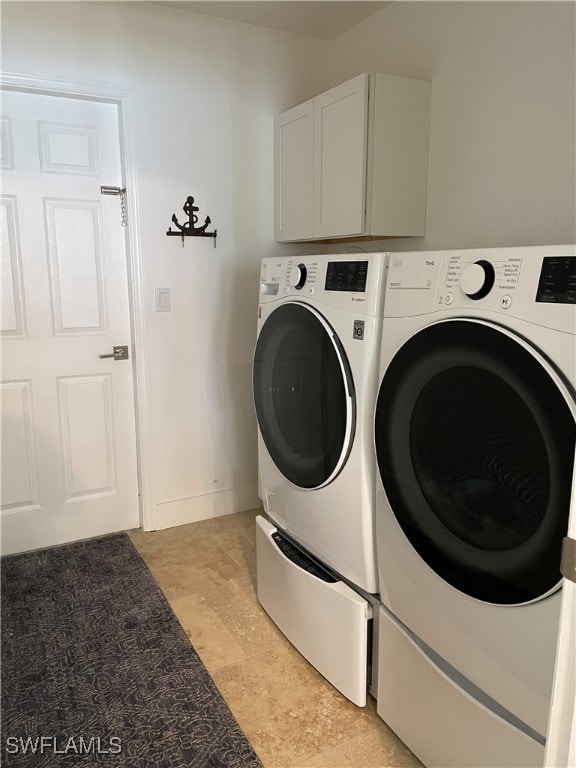 clothes washing area with cabinets and washing machine and dryer