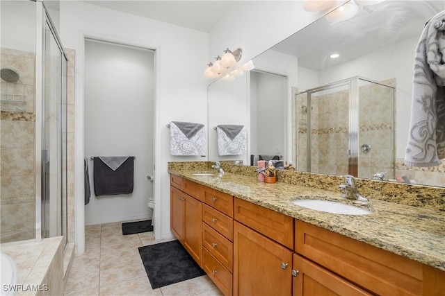 bathroom featuring toilet, vanity, tile patterned floors, and a shower with door