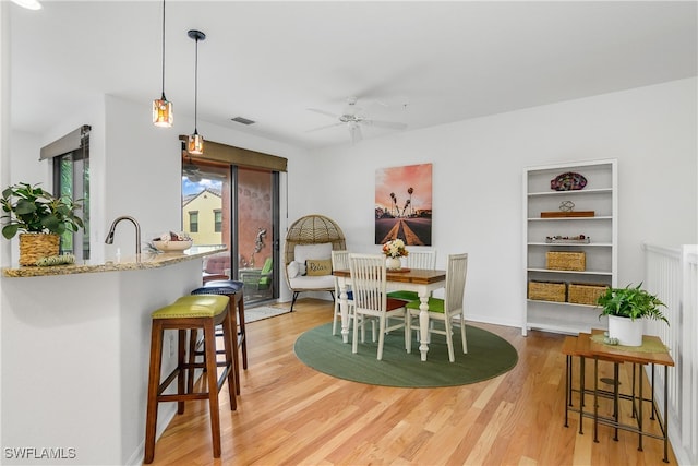 dining room featuring ceiling fan, sink, and light hardwood / wood-style floors