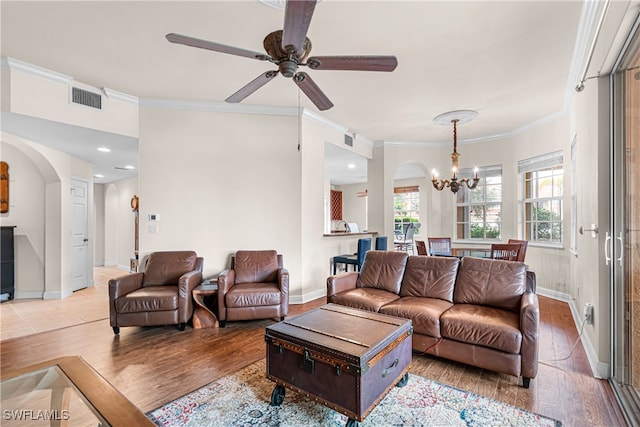 living room with ornamental molding, light wood-type flooring, and ceiling fan with notable chandelier